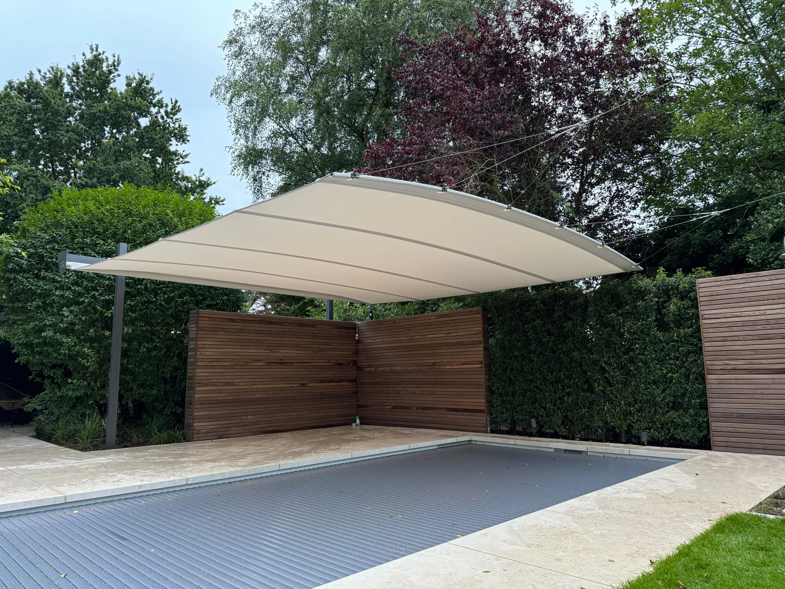 An Öhrra Square retractable shade sail drawn across a pool in a freestanding installation